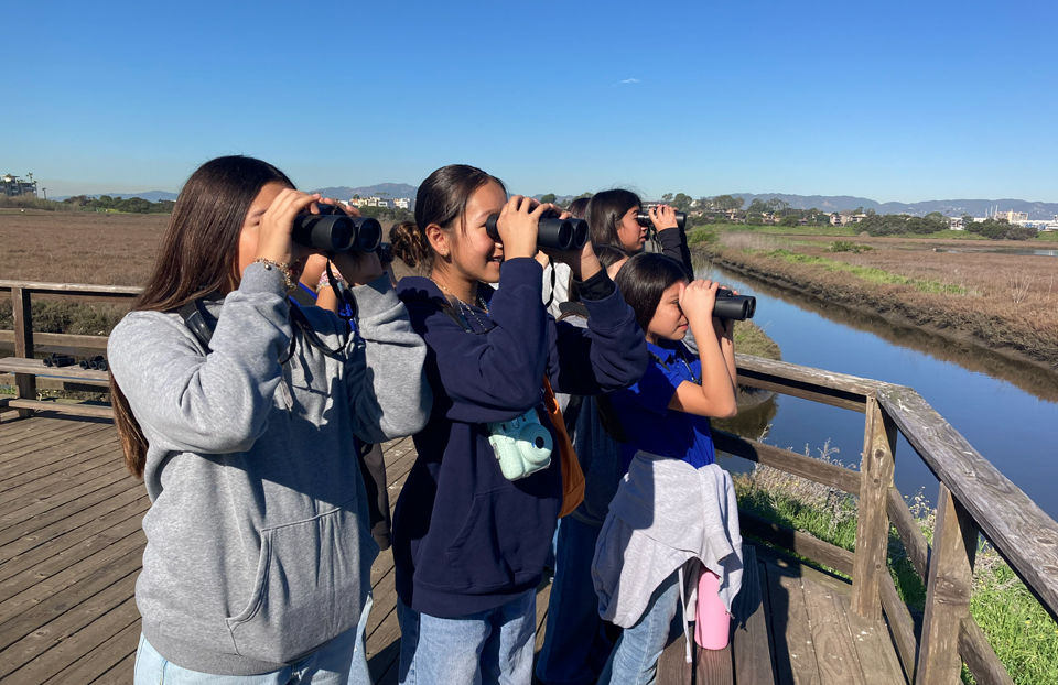 2026 Earth Day Blog Post featuring our STEM Action Grantees. In the image, Friends of Ballona Wetlands with students using binoculars to look at landscape.