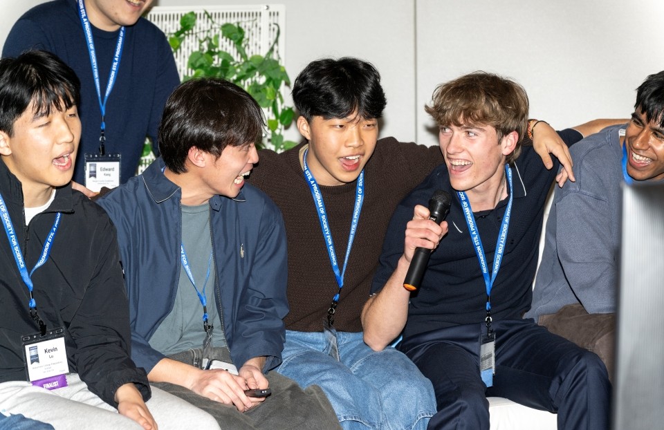 A group of Regeneron STS finalists sit side by side, singing karaoke