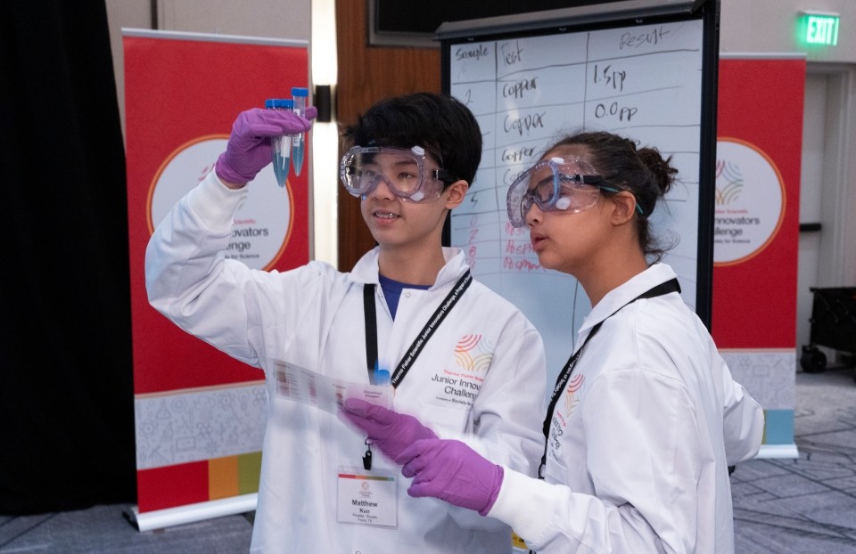 Two Thermo Fisher JIC finalists examine a test tube while participating in a challenge