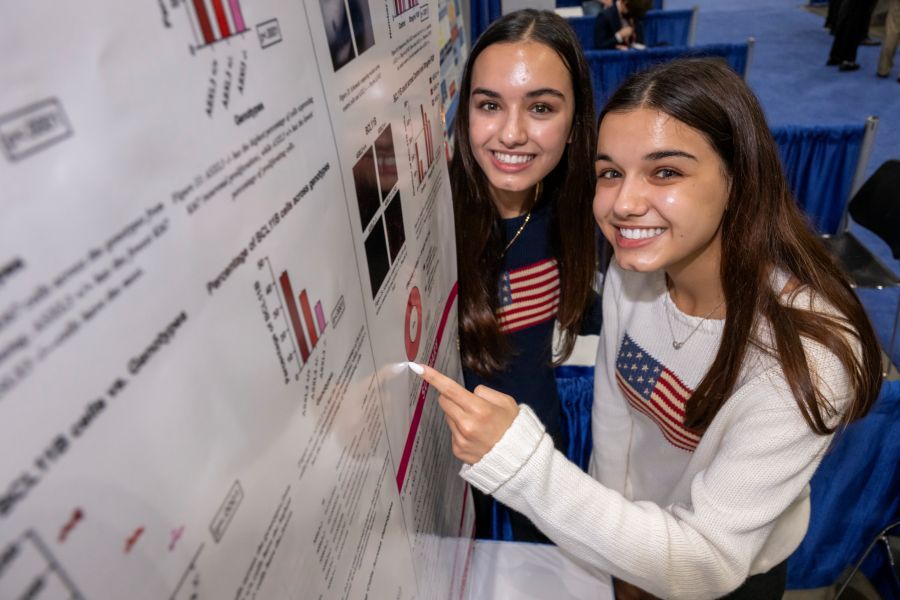 Lara and Maya Hammoud pose beside their research on ASXL3 and neurodevelopmental disorders at Regeneron ISEF 2024.